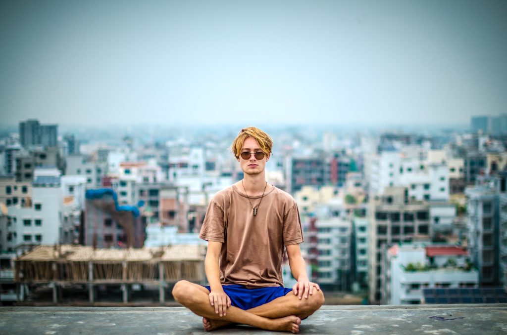 تصویری از یک شخص در حال مدیتیشن در شهری شلوغ؛ نمادی از مدیریت اضطراب با مایندفولنس